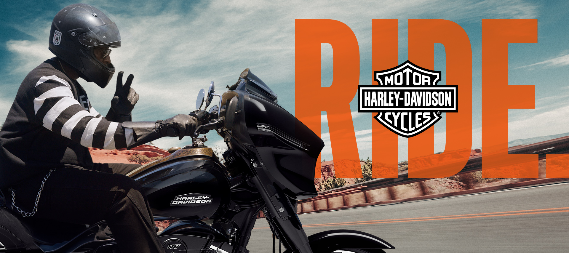 A motorcyclist riding black road glide making peace sign