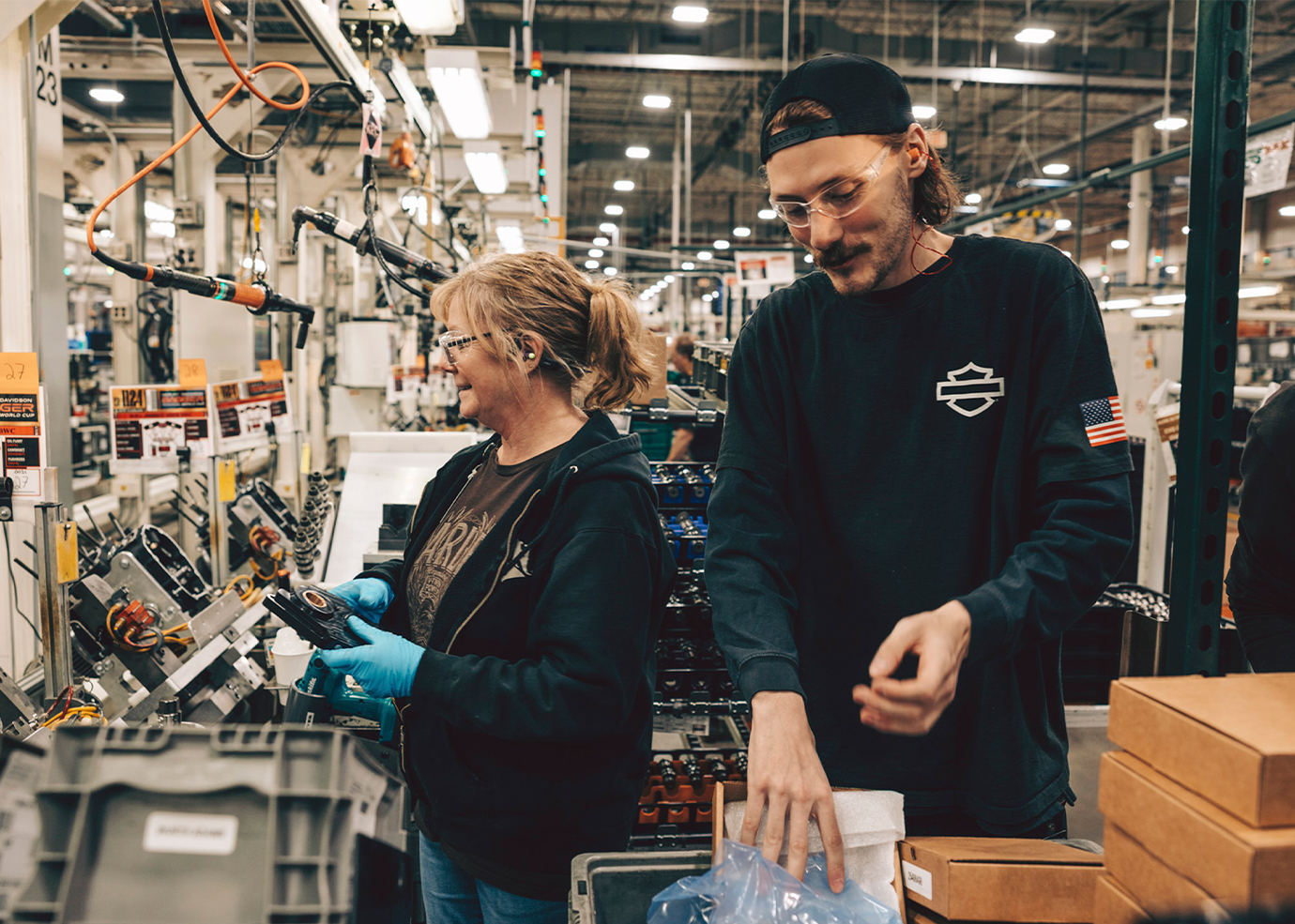 Two workers assemble motorcycle components on the factory floor