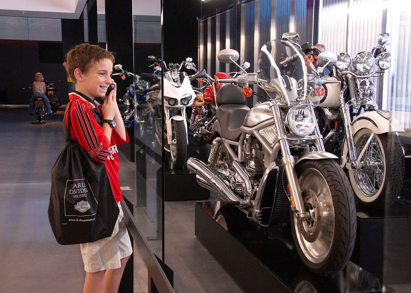 A visitor with a tote bag viewing a row of HD motorcycles